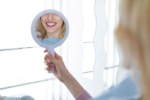 mujer mirando su sonrisa en espejo